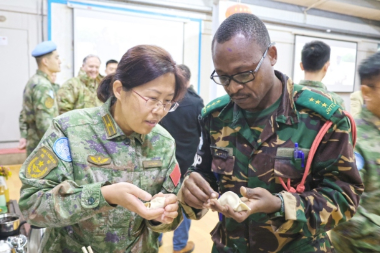 圖為維和官兵與外軍人員共同包餃子。胡光明攝