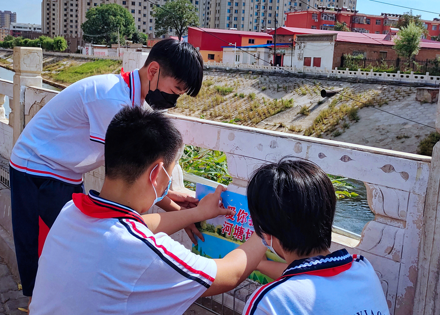 徐水小學(xué)學(xué)雷鋒志愿者在瀑河河邊張貼防溺水警示標(biāo)語。 徐水區(qū)委宣傳部供圖