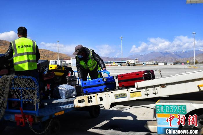 圖為機(jī)場工作人員傳送旅客行李箱?！≈芎?攝