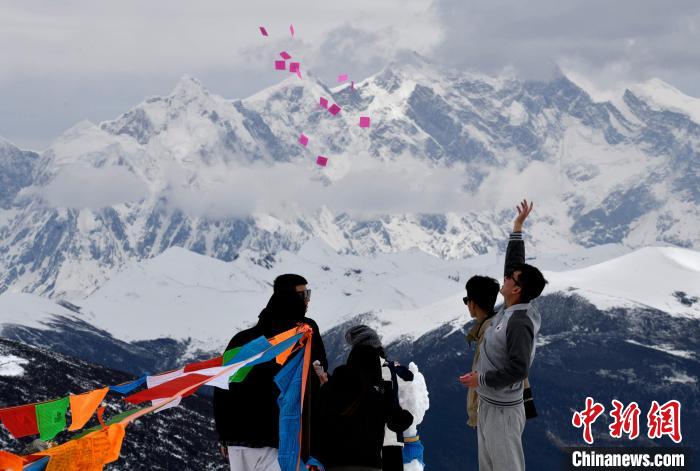 圖為5月14日，游客在西藏林芝色季拉山觀景臺(tái)拋灑“隆達(dá)”(風(fēng)馬旗，藏族民眾的一種祈福方式)?！±盍?攝