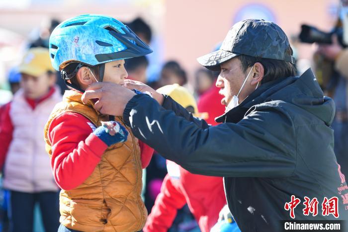 圖為拉薩市實(shí)驗(yàn)幼兒園孩子在教練的幫助下穿戴頭盔?！『闻罾?攝